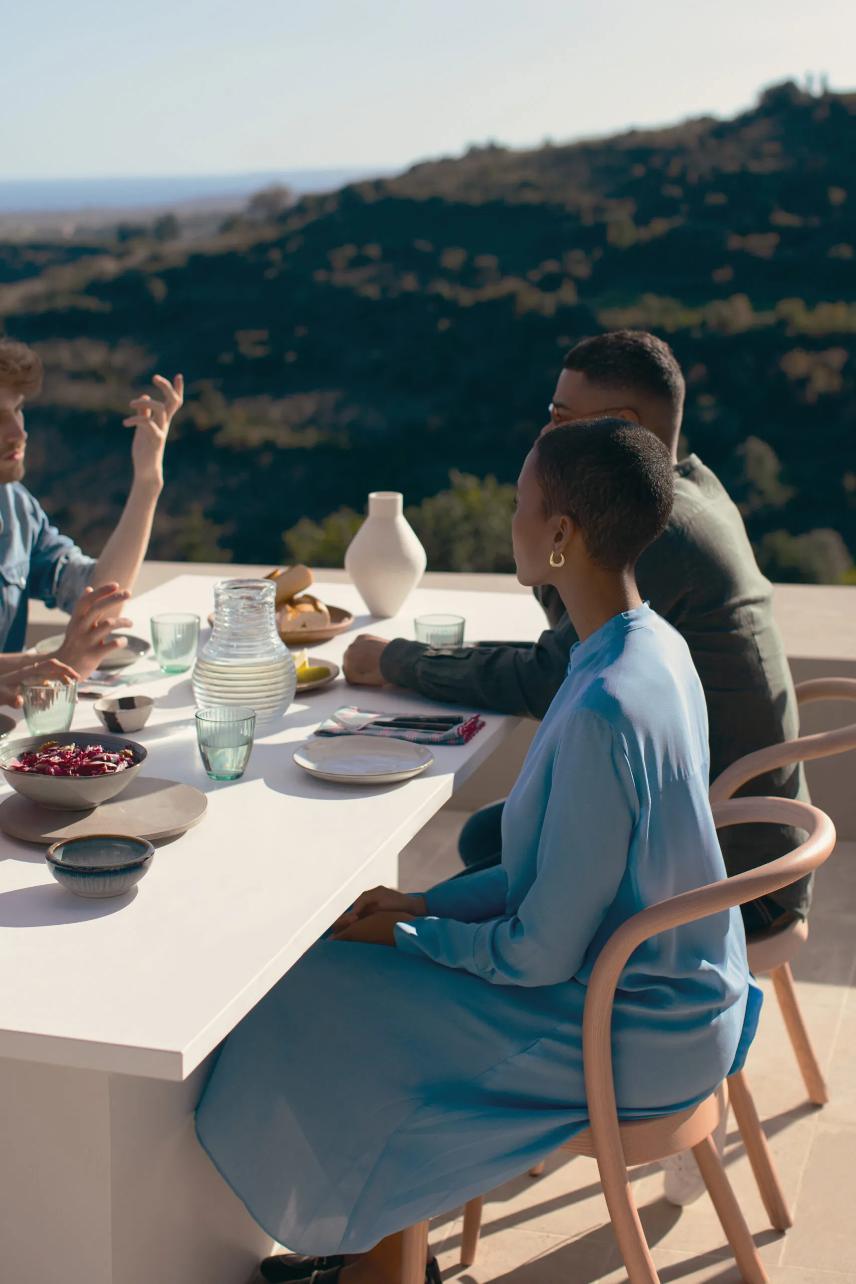 Group dining outdoors around a Caesarstone quartz table with mountain views in the background.